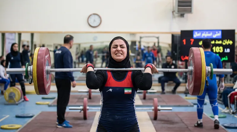 A weightlifter in the front rack position, showing the barbell resting on the shoulders with high elbows.