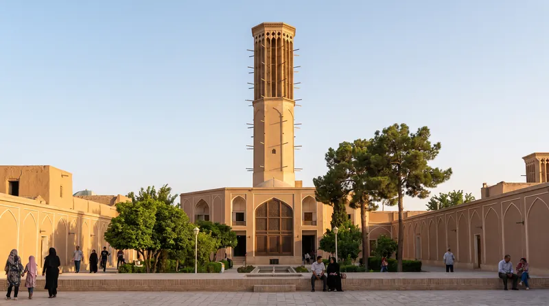 نمای پایین به بالای یک بادگیر بلند خشتی هشت‌وجهی در زیر آسمان آبی روشن