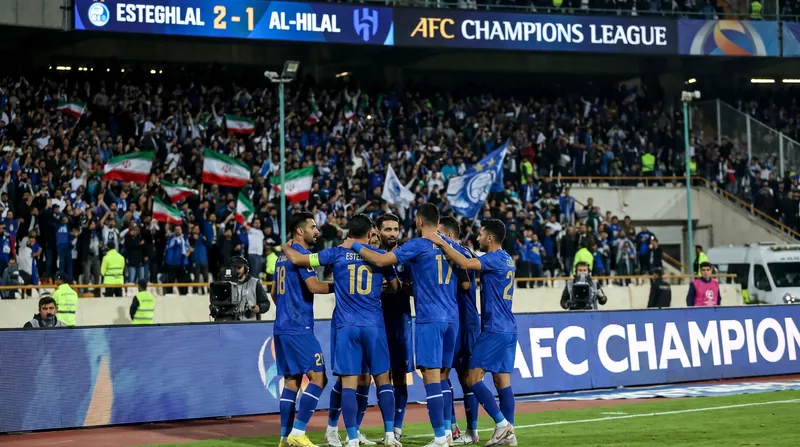 بازیکنان تیم فوتبال استقلال با لباس‌های آبی در حال خوشحالی پس از به ثمر رساندن گل در ورزشگاه