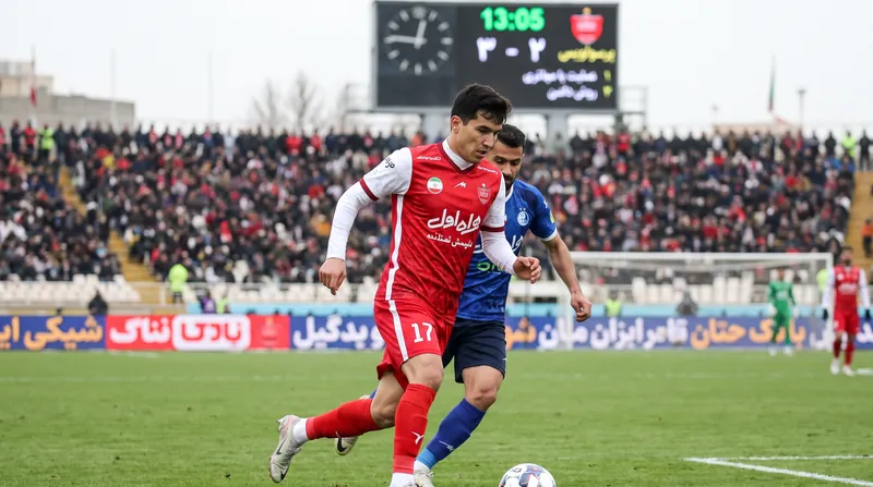 اوستون اورونوف با پیراهن پرسپولیس در حال حرکت با توپ در جریان یک مسابقه فوتبال