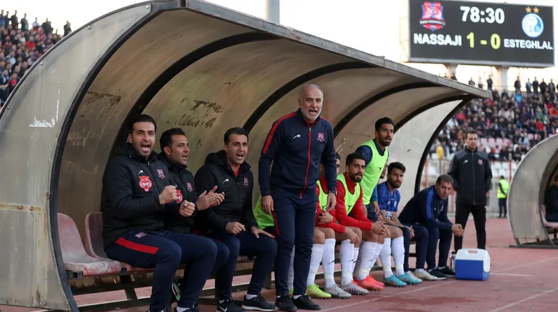 Empty managerial bench at a football stadium with red seats, symbolizing a coach's departure.