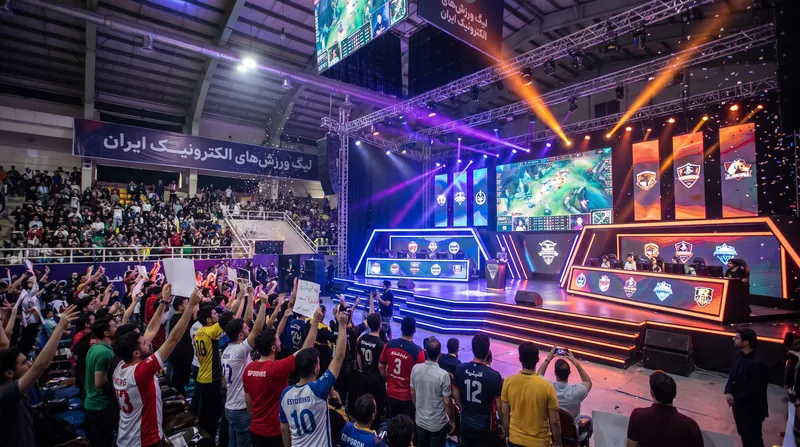 An empty professional esports tournament stage with glowing neon lights and large screens.