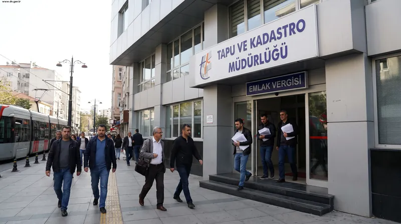 A smartphone showing a real estate app placed on top of Turkish tax documents and a title deed.