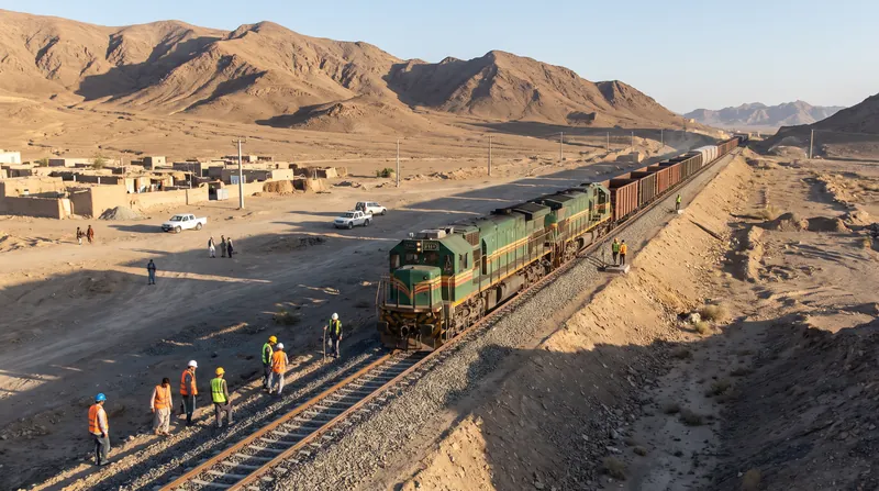 Newly laid railway tracks extending through the desert landscape of Sistan and Baluchestan under clear skies.
