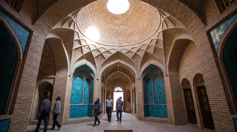 فضای داخلی یک هشتی سنتی ایرانی با سقف گنبدی آجری، در چوبی و سکوهای نشستن سنگی زیر نور ملایم.