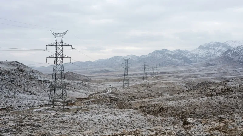نمای گسترده از یک نیروگاه حرارتی در ایران در فصل زمستان با برج‌های خنک‌کننده و خطوط انتقال برق