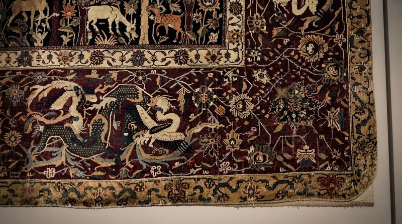 هزاران مرد سیاه‌پوش با چوب‌دستی‌های بلند در حال حمل یک قالی لوله‌شده سنتی در فضای باز و غبارآلود مشهد اردهال.