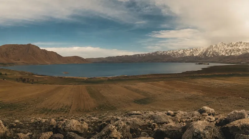 نمای گسترده از تالاب چغاخور با آب‌های آبی روشن، نیزارها و کوه‌های پس‌زمینه در استان چهارمحال و بختیاری.