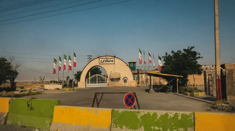 نمای بیرونی دیوارهای بلند و برج مراقبت یک زندان فوق امنیتی با سیم خاردار در زیر آسمان ابری